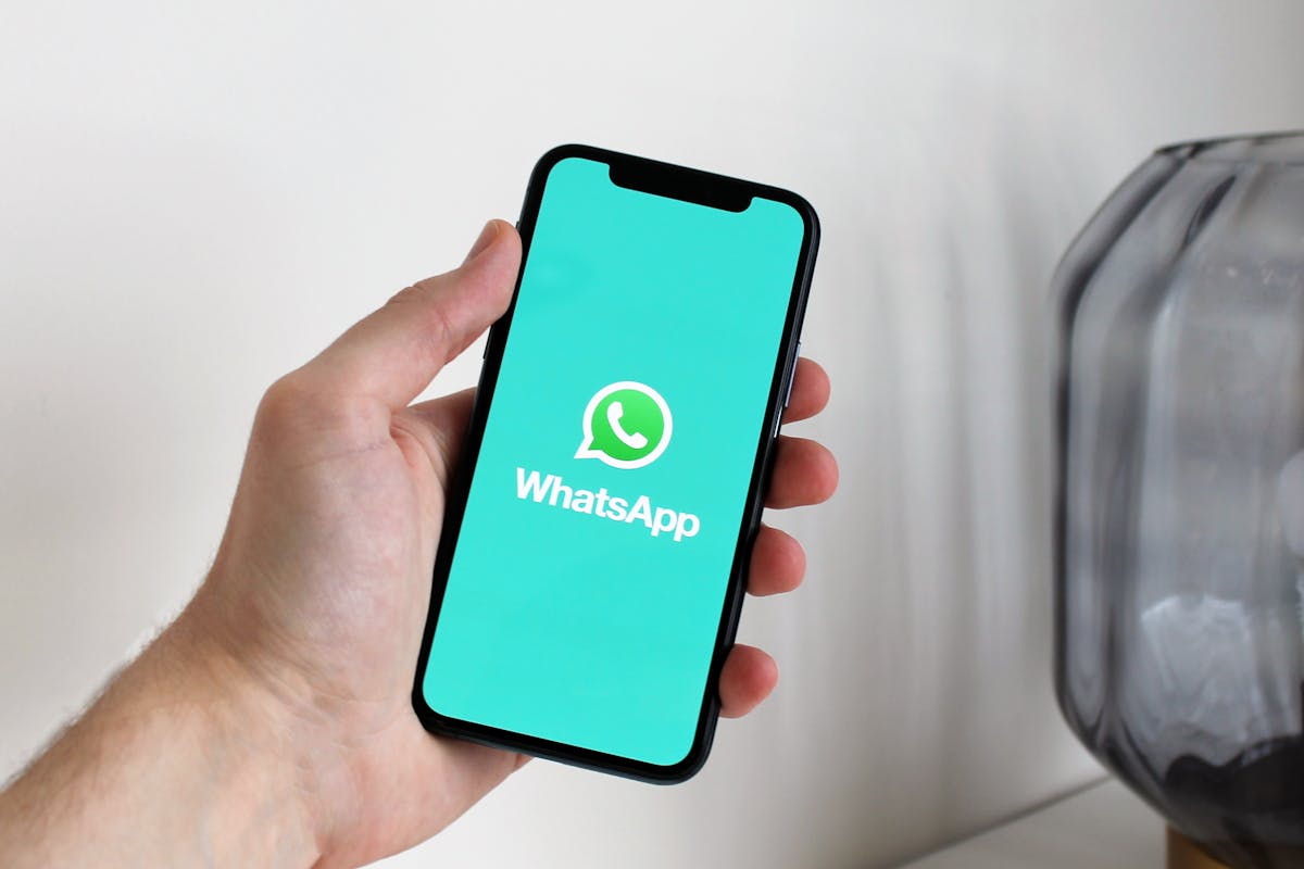Hand holding a smartphone displaying the WhatsApp app logo, representing a Singapore property agent preparing a post-viewing follow-up message