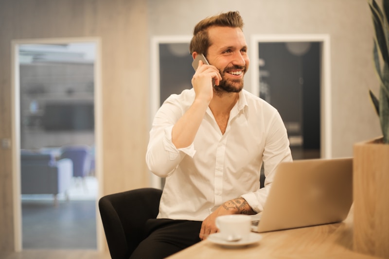 Property agent on a phone call with laptop open, managing client communications from a modern workspace