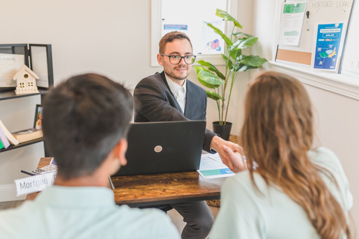 Mortgage broker meeting with a young couple to discuss rates and loan options in an office